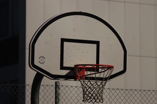 Close-up of a basketball hoop with chain net, set against an urban building background.