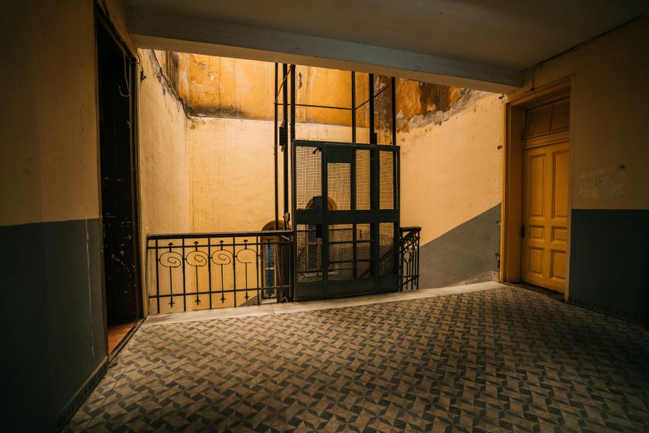 Old elevator in a vintage hallway with geometric tiled floor. Rustic charm and design.
