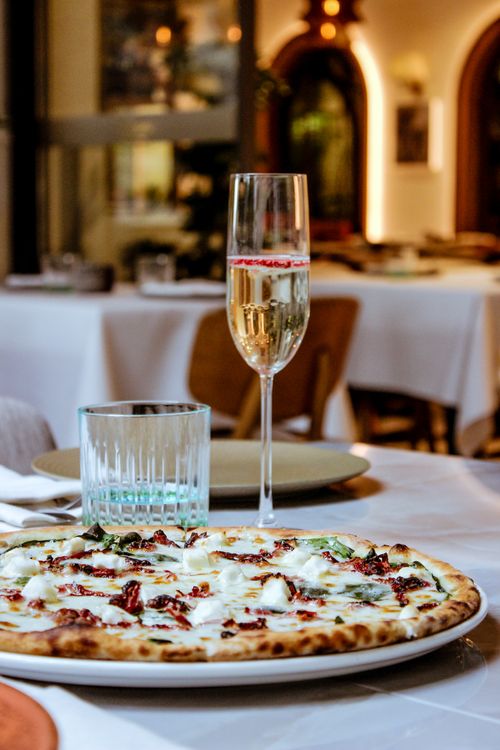 Free Italian pizza served with champagne in an elegant restaurant setting, perfect for gourmet experiences. Stock Photo
