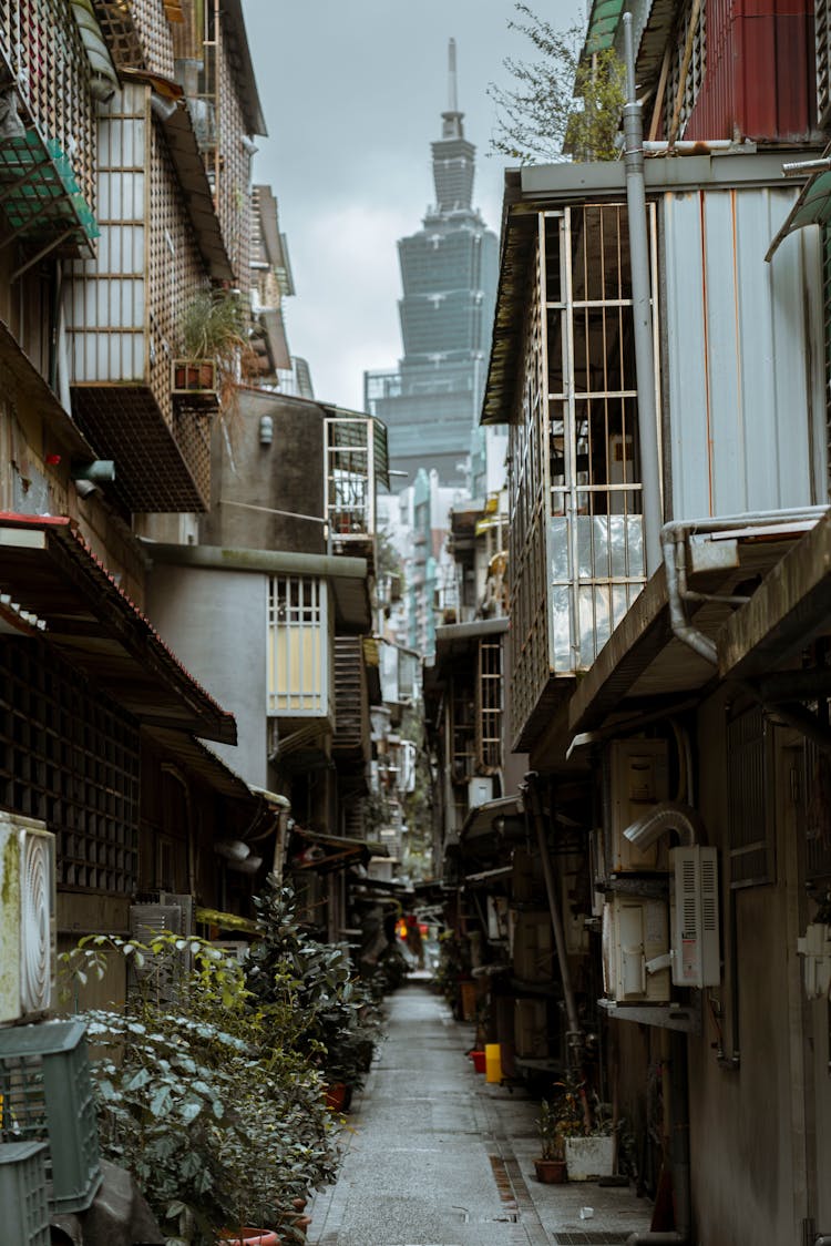 Narrow Alley In Taipei With The View Of A Skyscraper Between Houses