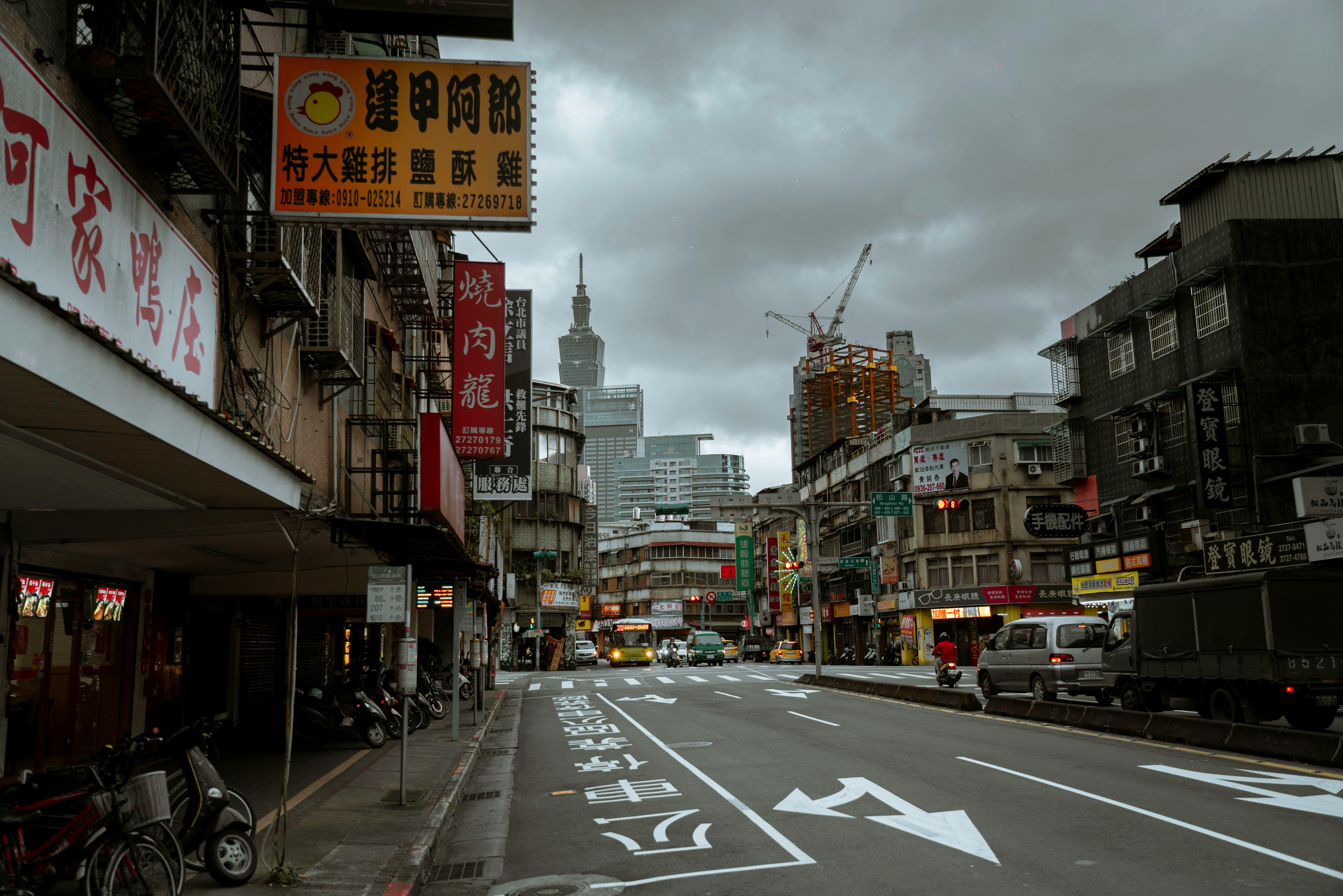 Dynamic city street view with buildings, vehicles, and an overcast sky.
