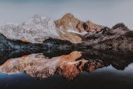 白雪皑皑的山峰倒映在平静的湖面上，展现出令人惊叹的山地景观与自然的宁静