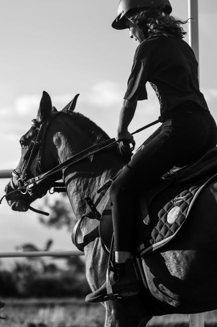 A woman riding a horse in black and white, showcasing equestrian sportsmanship and style.