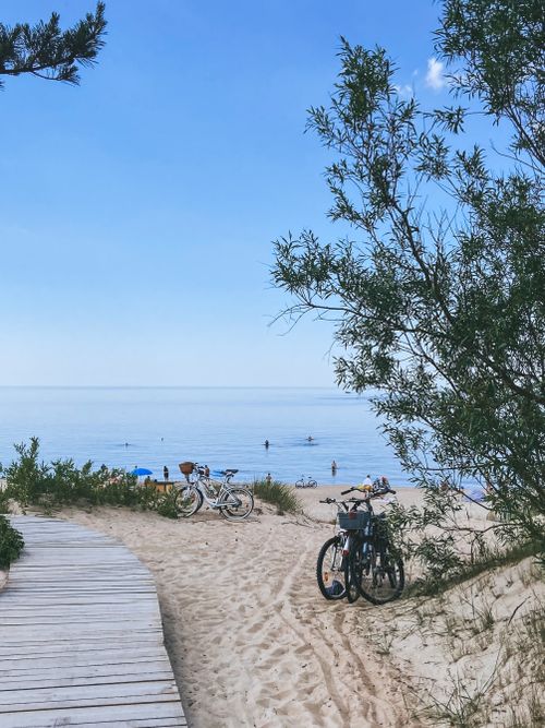 Free Peaceful beach scene with sandy path, bicycles, and clear blue sky perfect for a summer getaway. Stock Photo