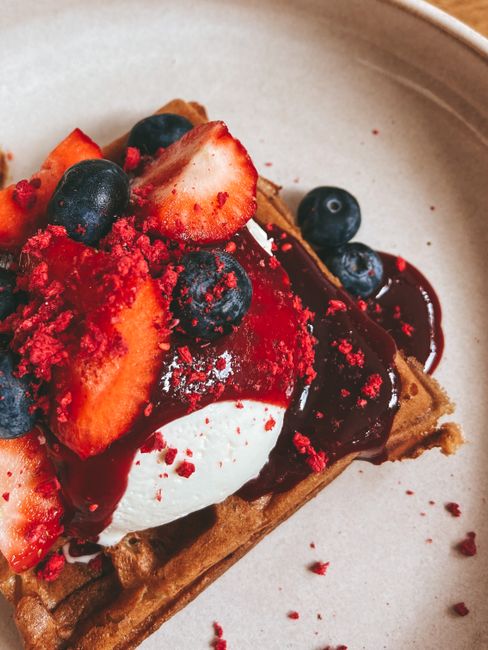 Close-up of a waffle topped with strawberries, blueberries, and ice cream.