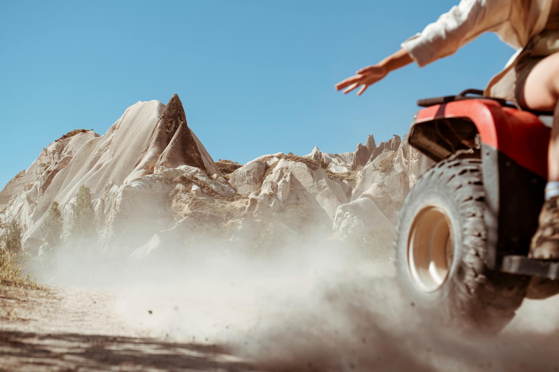 Dynamic shot of an ATV kicking up dust in a dramatic rocky desert setting.