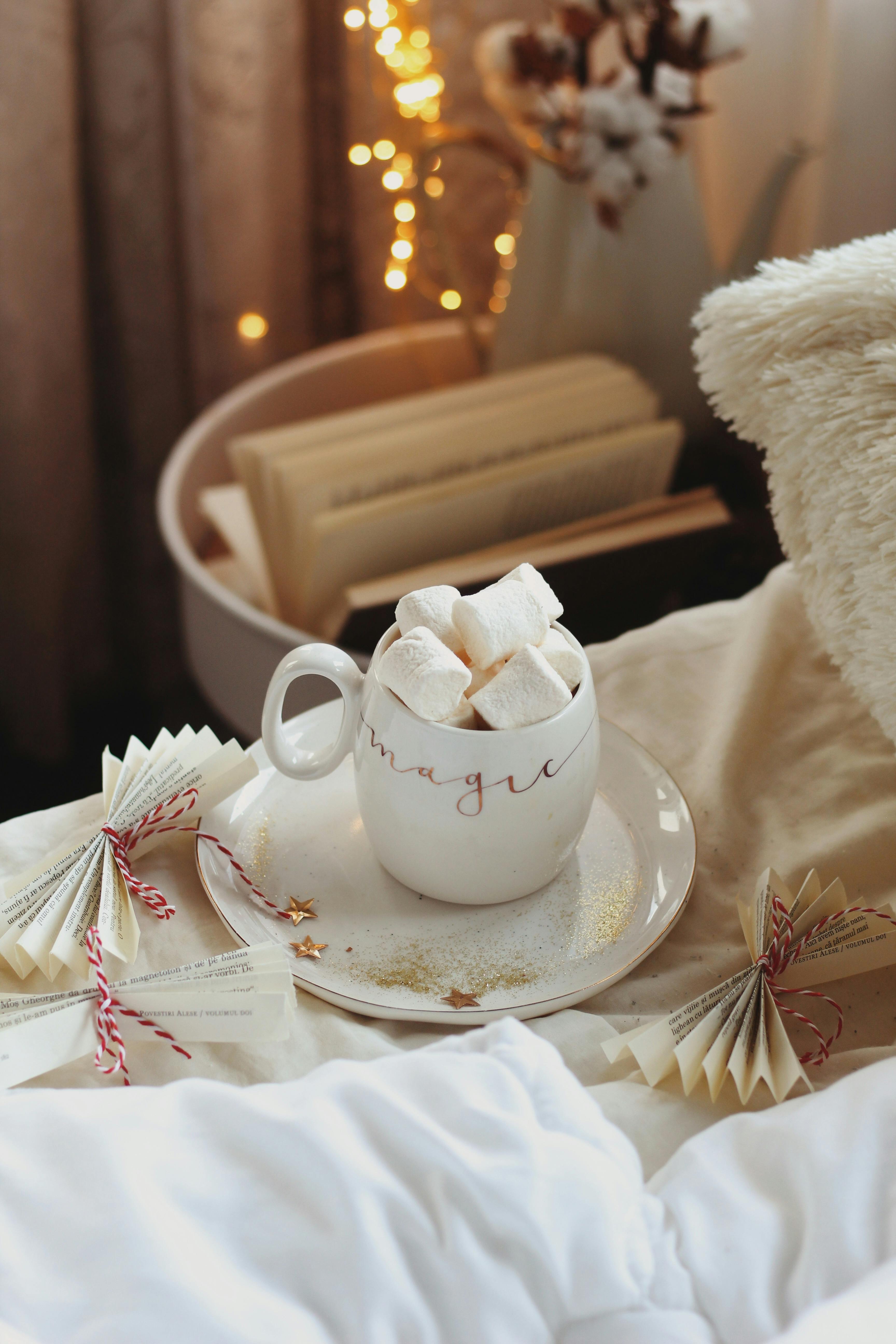 elegant mug with hot chocolate and marshmallows on a bed in a cozy bedroom