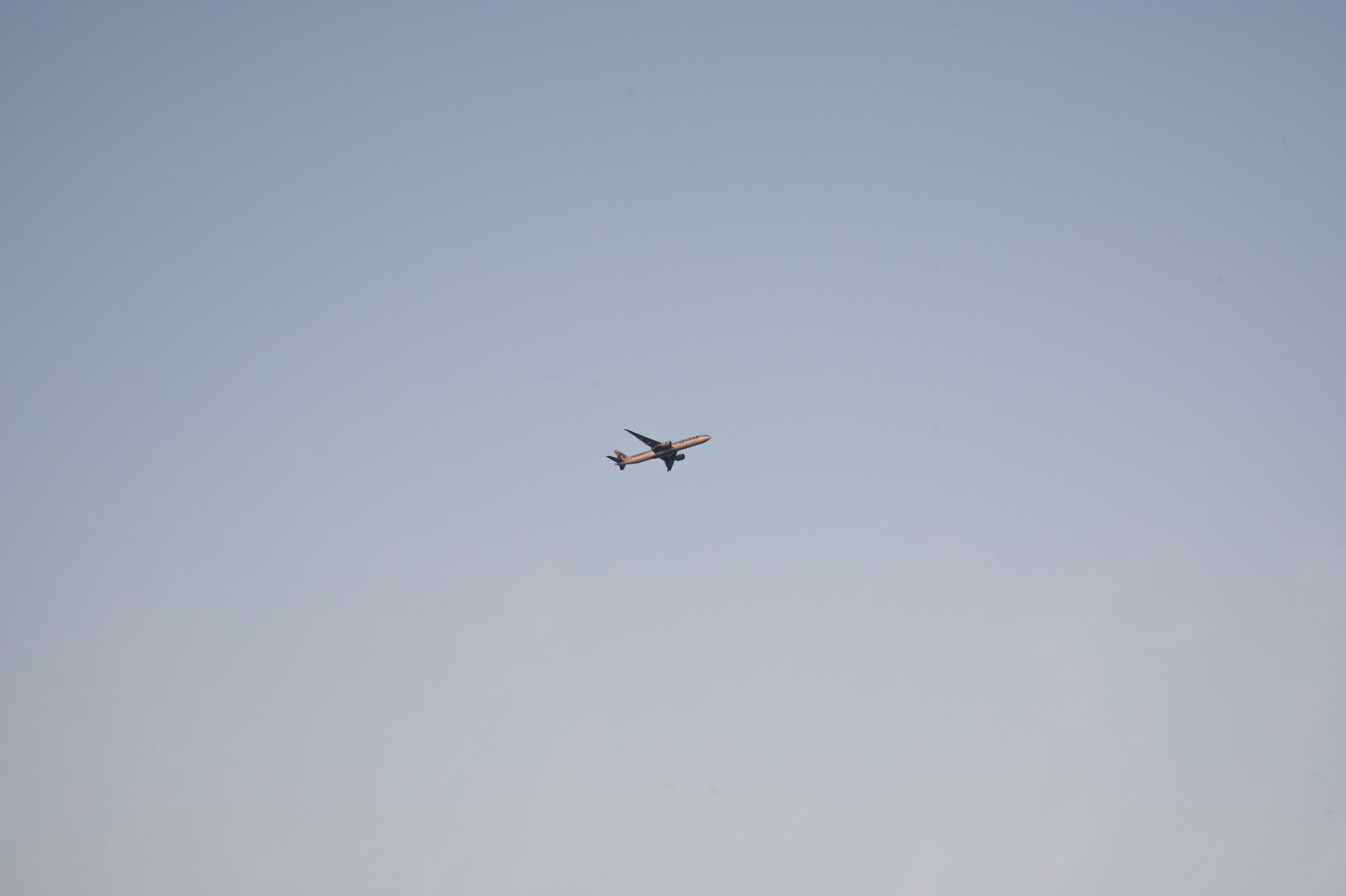 A solitary passenger airplane flying in a clear blue sky above Doha, Qatar.