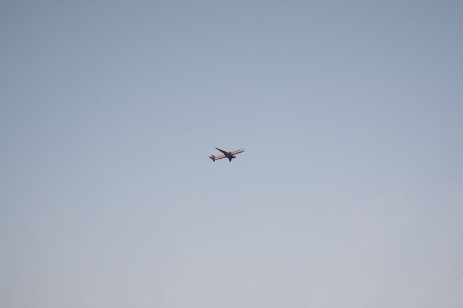 A solitary passenger airplane flying in a clear blue sky above Doha, Qatar.