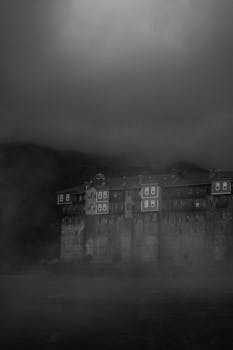 Moody black and white photo of a foggy, dark monastery in Greece.