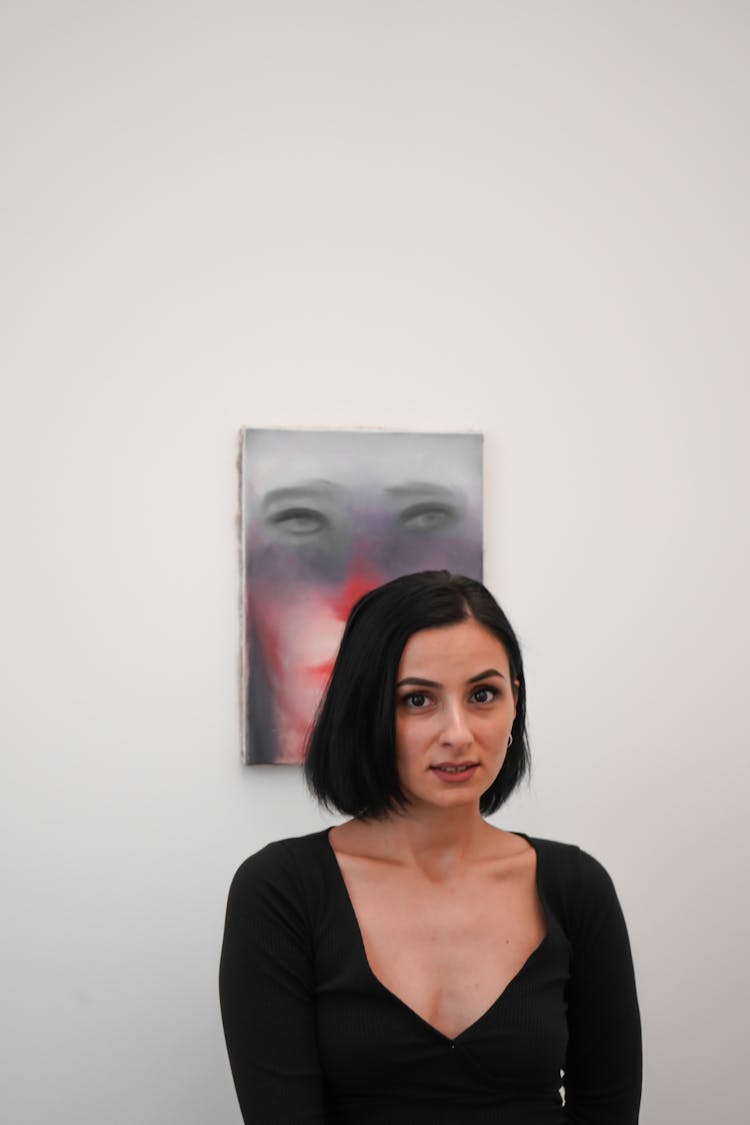 Woman In Black Dress Standing Near A Painting On Wall