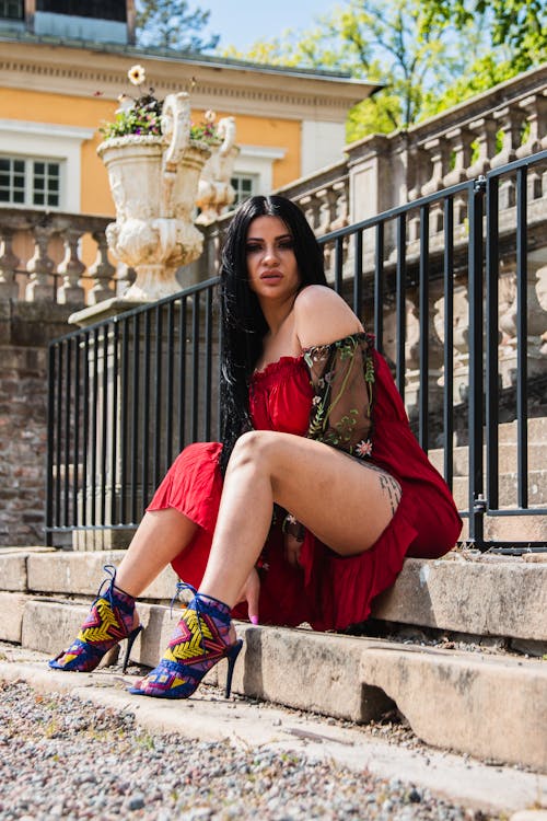 Woman in a Red Dress and High Heels Sitting on Steps 