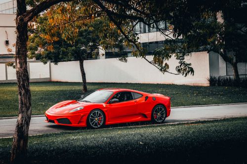 Free Eye-catching red sports car parked on a tree-lined street in urban setting. Stock Photo