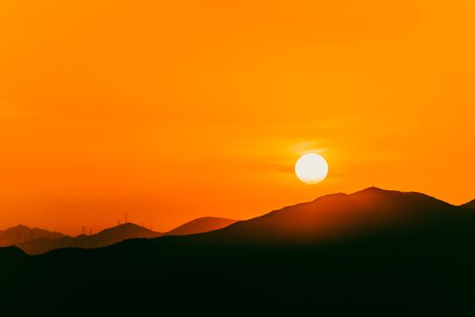 Stunning photo of a vibrant sunset casting silhouettes over a tranquil mountain landscape.