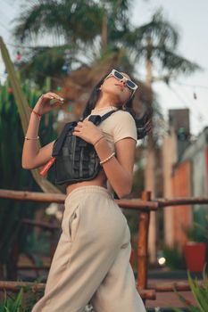 Fashionable woman showcasing modern style with sunglasses and vest outdoors.