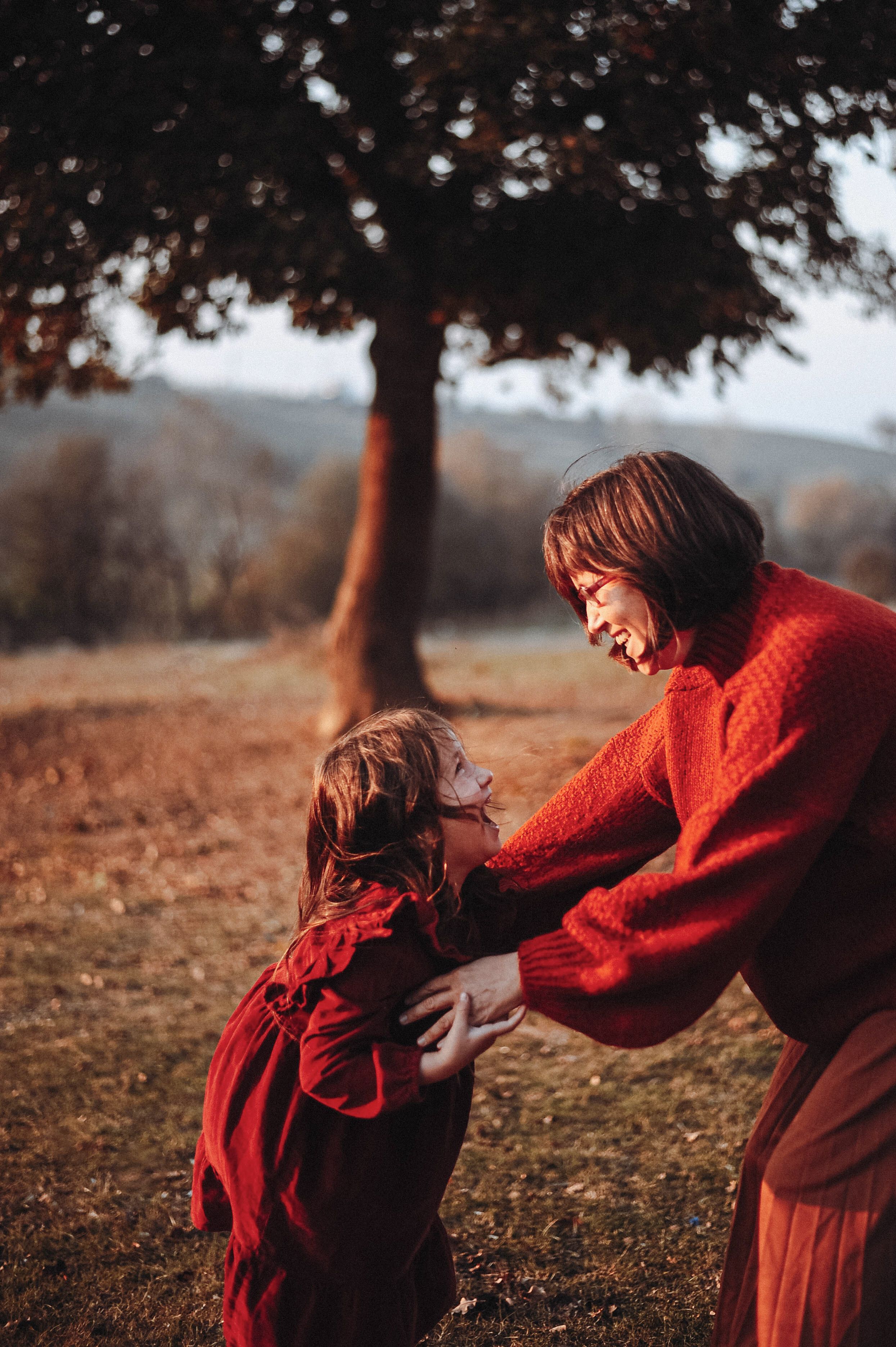 Joyful moment between mother and daughter playing at the park during fall.