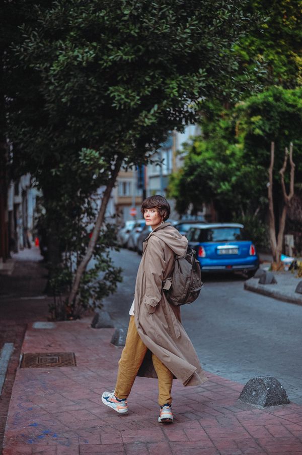 Trench coat layered over hoodie with sneakers