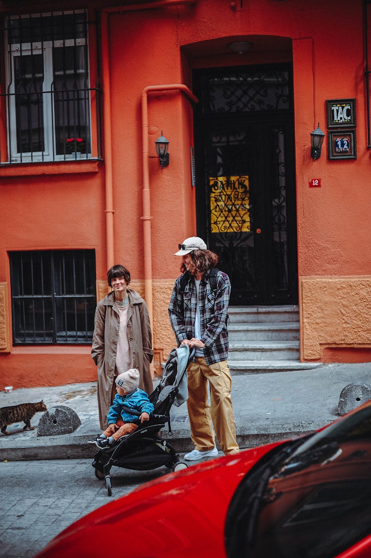 Couple Standing On The Street With Baby In A Stroller