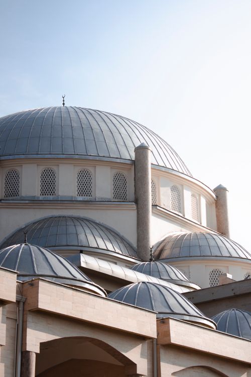 Free A serene view of mosque domes shining in sunlight against a clear blue sky. Stock Photo