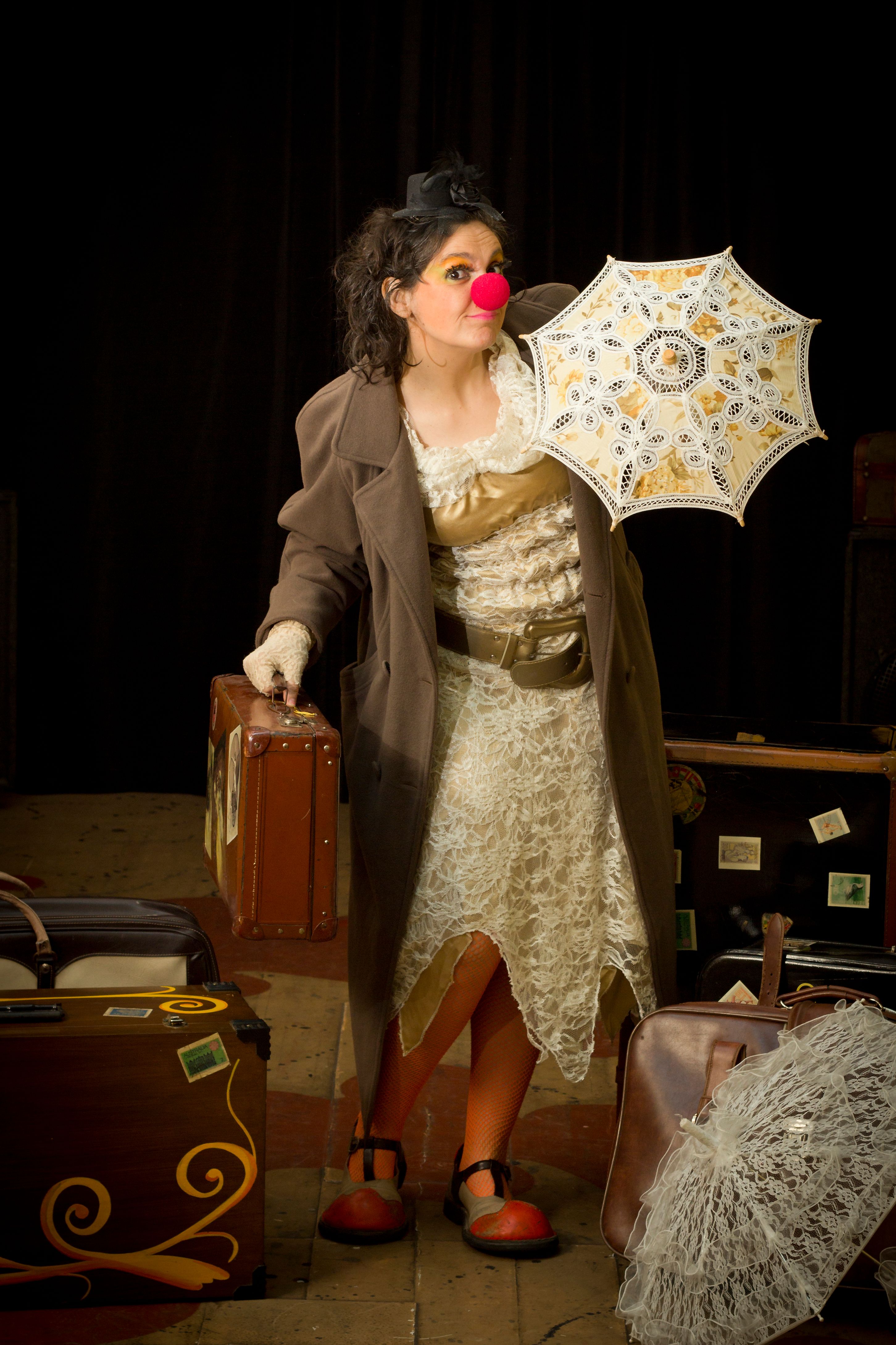 A whimsical clown dressed in vintage attire with a parasol and luggage on a black background.