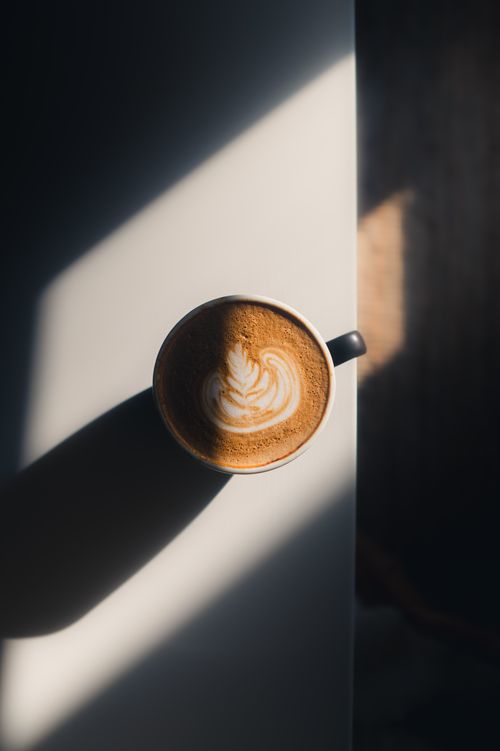 Free A minimalist top-view latte with artistic latte art in soft lighting on a white table. Stock Photo