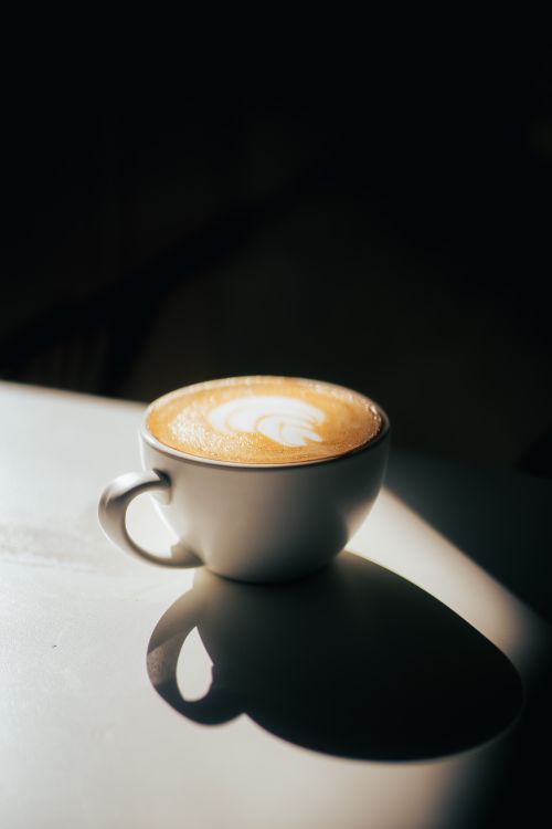 Free Captivating shot of cappuccino with latte art, showcasing dramatic shadows. Stock Photo