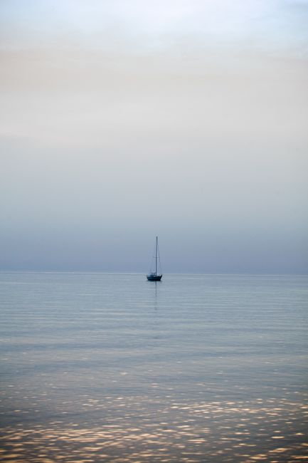 A lone sailboat on calm waters under a serene sky, creating a peaceful seascape.