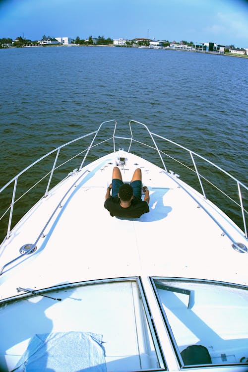 Man Sitting on White Boat