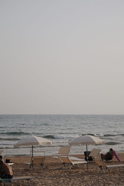 Serene beach scene with umbrellas and lounge chairs on a sunny day.