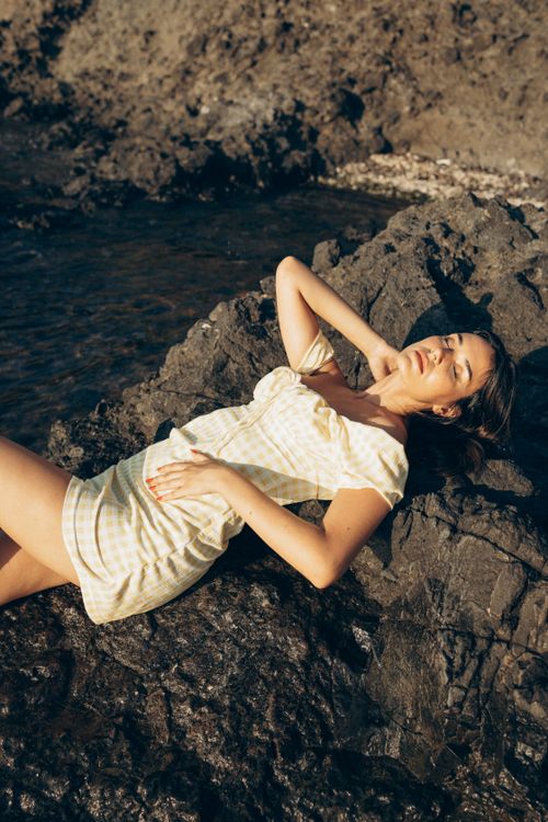 Free A woman in a light dress lies on rocky terrain by a river, enjoying the sun in Turkey. Stock Photo