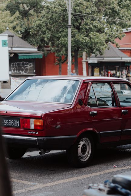 Vintage red car parked on a city street showcasing urban retro charm.