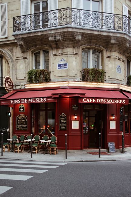 Classic Parisian café with outdoor seating, located in a charming urban corner setting.
