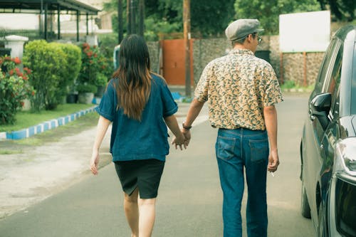 A Couple Walking Hand in Hand Near Black Car