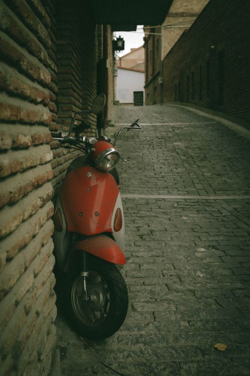 Free A red moped parked against a wall on a cobblestone street in Tbilisi, Georgia. Stock Photo