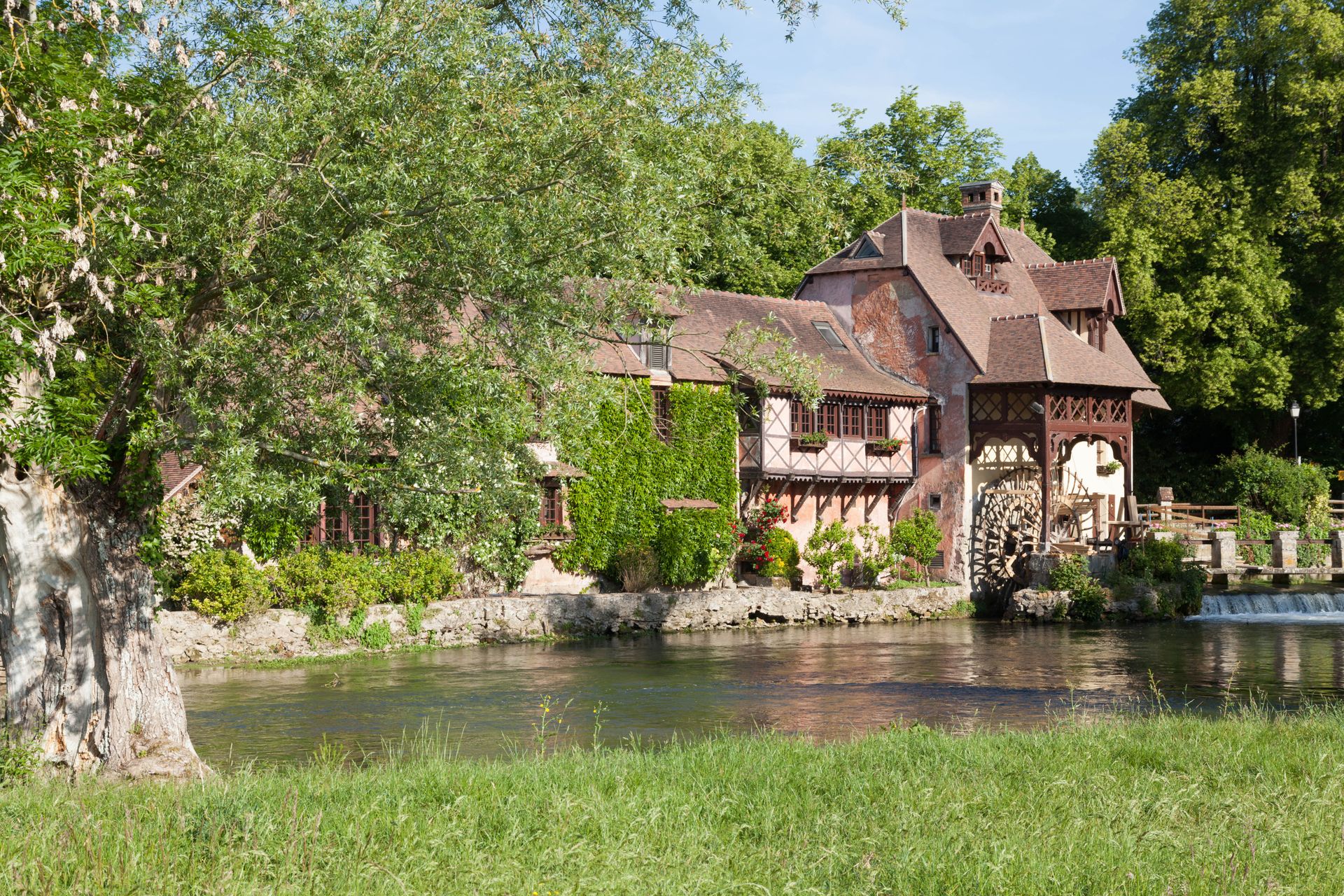 Charming summer scene of Le Moulin de Fourges mill by a river in Normandie, France.