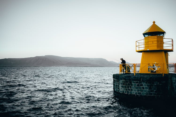 Fisherman By Small Lighthouse