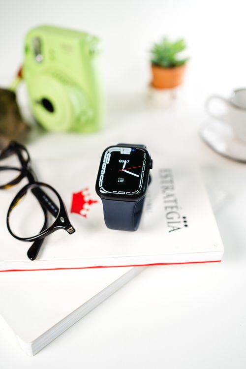 Free Close-up of a smartwatch and eyeglasses on a book, highlighting modern technology and style. Stock Photo