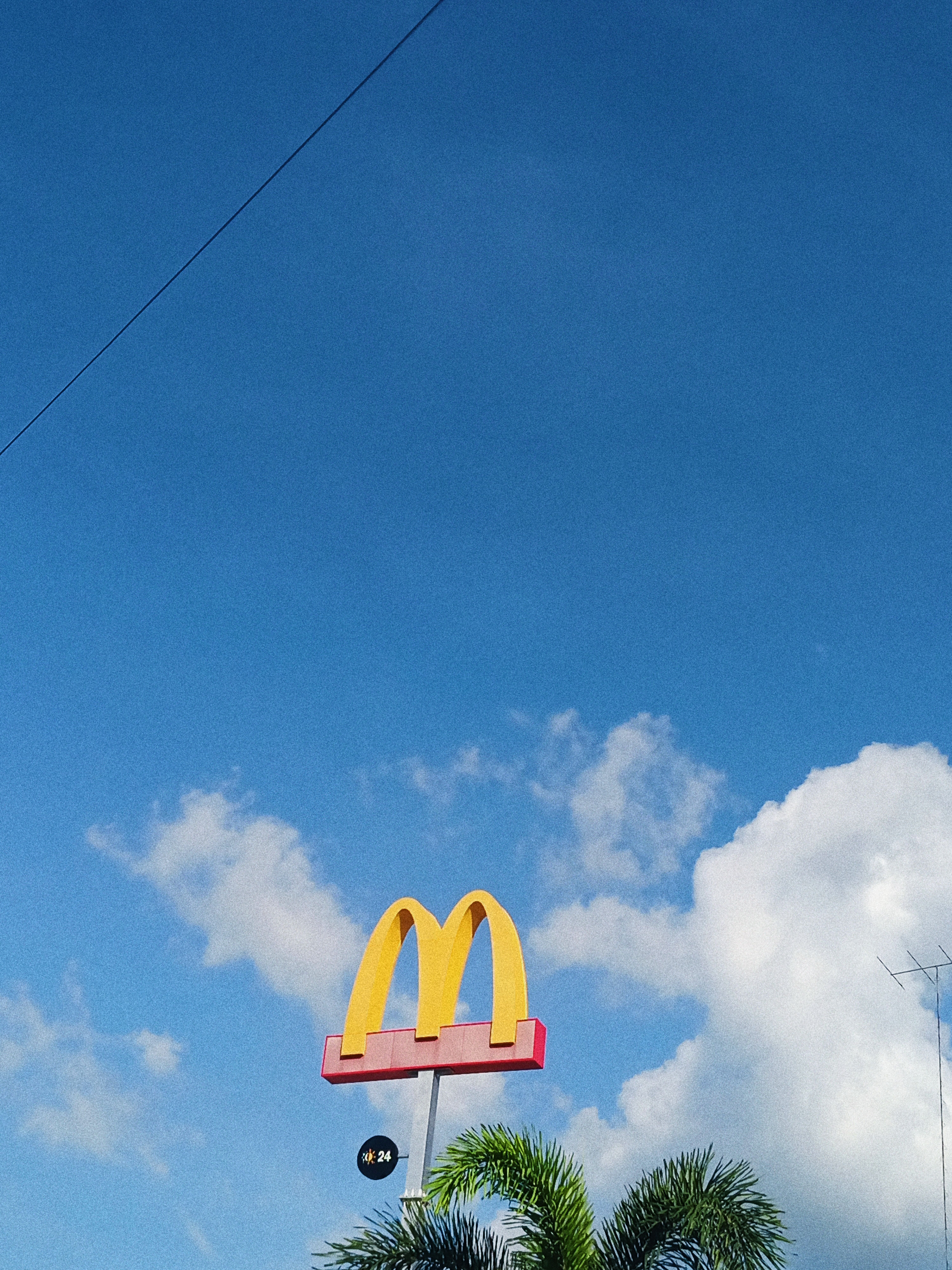 Bright photo of a fast food sign against a clear blue sky, capturing minimalism and bold colors.