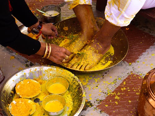 Close-up of a Prewedding Haldi Ceremony where Feet of the Groom are Covered in Yellow Powder 