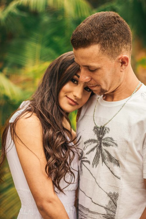 Free Couple sharing a tender moment outdoors with lush greenery in the background. Stock Photo