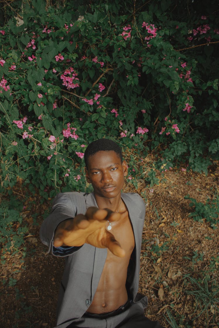 Shirtless Man Lying On Ground Reaching His Hand Out