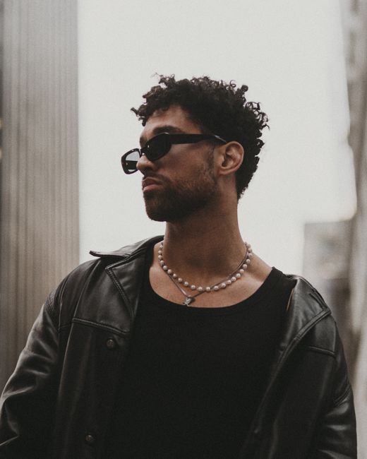 Stylish man in leather jacket and sunglasses in urban environment.