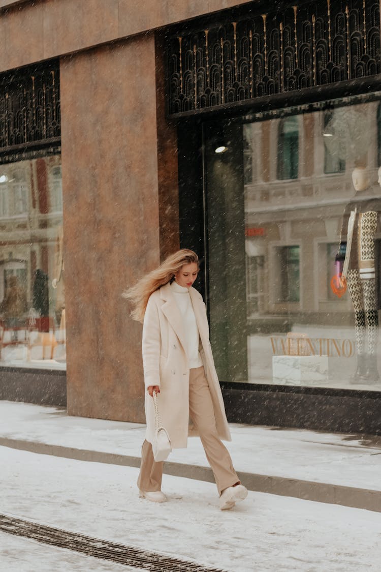 Woman In Coat Walking In Town In Snow