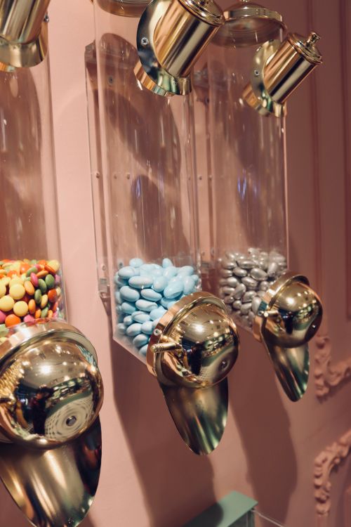 Free Close-up view of colorful candies in gold and glass dispensers, evoking a retro vibe. Stock Photo