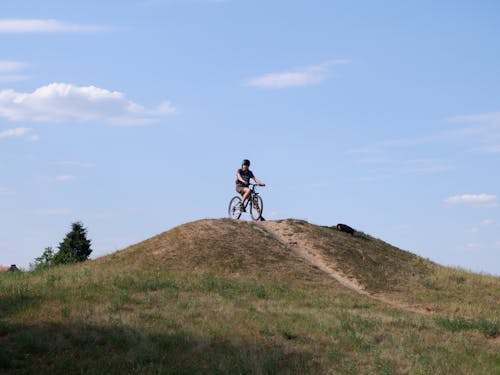 Man in Black Shirt Riding a Bicycle on Hill