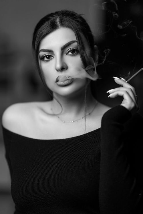 Free Elegant black and white portrait of a woman smoking, exuding mystery. Stock Photo