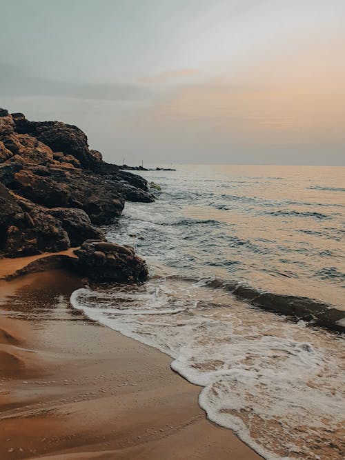 View of Waves Washing up the Rocky Shore and Beach at Sunset