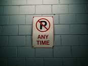 No parking sign against a gray brick wall, emphasizing traffic regulations.