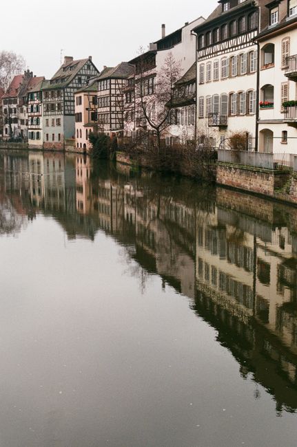 A serene view of traditional European buildings reflecting in a calm canal.