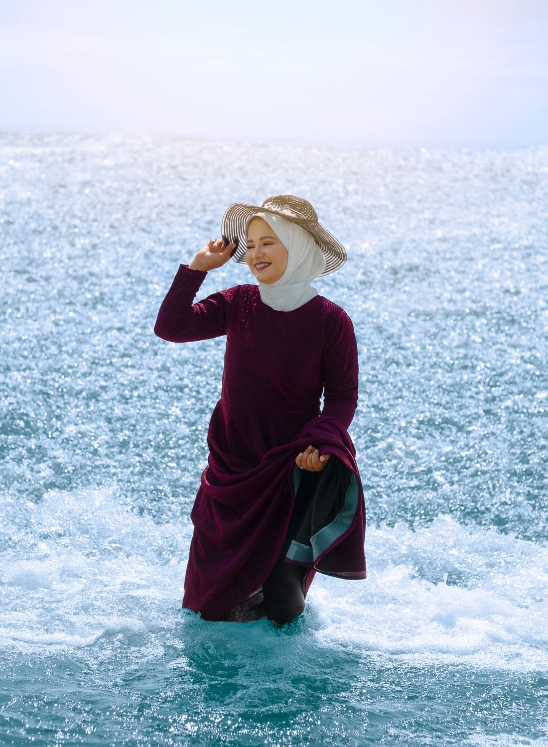 Asian woman wearing a hijab enjoying ocean waves and sunlight on a beach Asian woman wearing a hijab enjoying ocean waves and sunlight on a beach